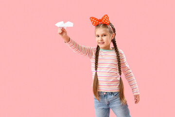 Little girl with paper plane on pink background. Children's Day celebration
