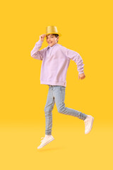 Little boy in party hat jumping on yellow background. Children's Day celebration