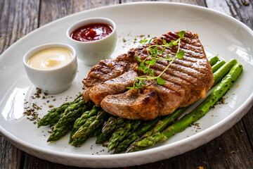 Barbecued pork neck and asparagus on wooden table