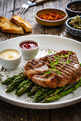 Barbecued pork neck and asparagus on wooden table