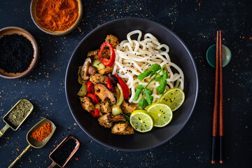 Chicken nuggets with noodles and stir fried vegetables on black table
