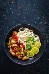 Chicken nuggets with noodles and stir fried vegetables on black table
