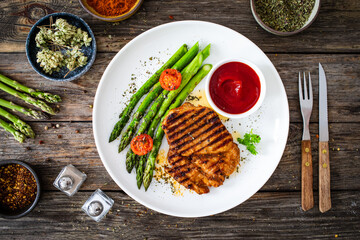 Barbecued meat and asparagus on wooden table