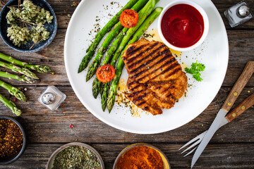 Barbecued meat and asparagus on wooden table