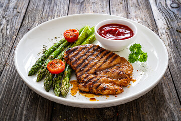 Barbecued meat and asparagus on wooden table