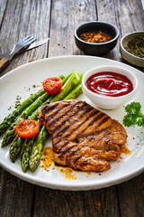 Barbecued meat and asparagus on wooden table
