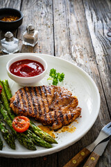 Barbecued meat and asparagus on wooden table