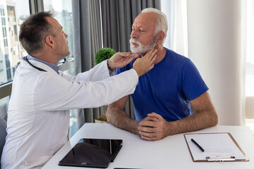 Doctor checking sore throat or thyroid glands of a senior patient by touching neck in hospital office. Thyroid cancer prevention concept - 602220220