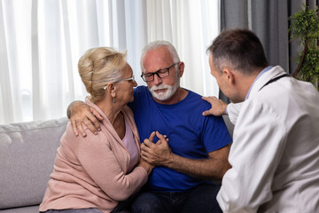 Distressed worried senior couple hugging after bad medical result while doctor is comforting them