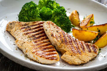 Barbecued turkey breast and broccoli on wooden table 