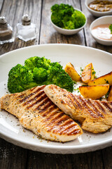 Barbecued turkey breast and broccoli on wooden table 