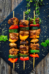 Fototapeta premium Meat skewers - grilled meat with vegetables on wooden background 