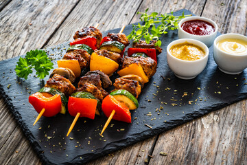 Meat skewers - grilled meat with vegetables on wooden background

