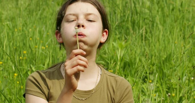 A girl is blowing dandelion seeds