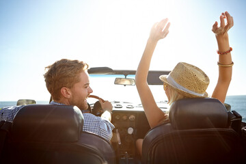 Car, road trip and freedom with a couple by the beach on a drive to enjoy the view during summer together. Travel, transport and driver with a woman sitting hands raised by the ocean with her man