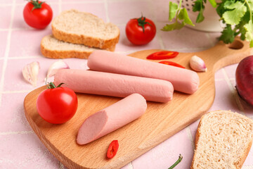 Board of tasty sausages with tomatoes on pink tile background