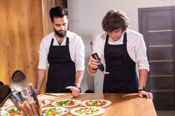 Chef pouring dressing over caprese salad in restaurant kitchen