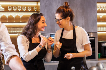 Two funny professional female chefs cooking food in large kitchen