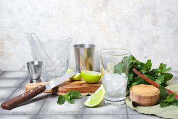 Glass with ice and ingredients for preparing mojito on table