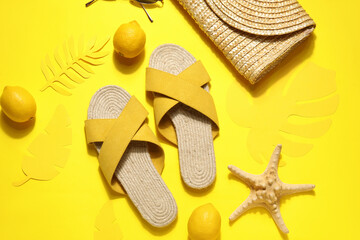 Wicker bag with flip flops and sunglasses on yellow background