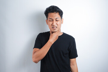 Young Asian man having sore throat and touching his neck, wearing a loose black t-shirt against white background. Hard to swallow