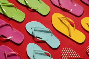 Many colorful flip flops on red background