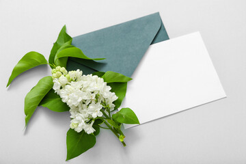 Envelope with blank card and beautiful lilac on grey background