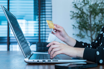 Young woman using laptop computer and holding credit card to shopping online, e-commerce and internet banking working from home. The payment method contactless money. Online shopping concept.