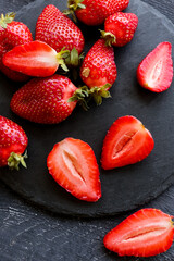 Board with fresh strawberries on black wooden background