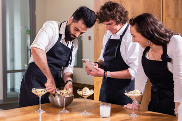 Chef teaching trainees how to make ice cream. Cooking tasty ice cream dessert made from chocolate and vanilla in glass bowl