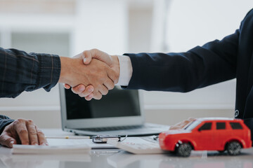 close handshake after signing a contract and paying successfully The car dealer or sales manager offers to sell the car and explains the terms of the car contract and insurance.