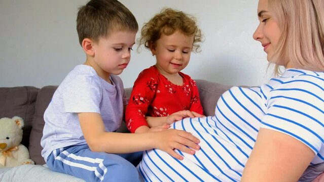 A pregnant woman hugs her son and daughter. Selective focus.