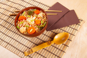Traditional Asian instant noodles meal with vegetables on wooden background