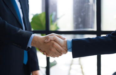 Two diverse professional business men executive leaders shaking hands at office meeting.