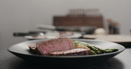 sliced new york steak with roasted asparagus on black plate