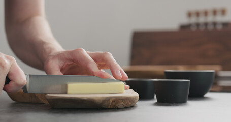 Obraz premium man cutting hard cheese with knife on wood board