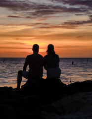Fototapeta na wymiar A couple of men and women are on the beach watching the sunset during vacation at Aruba Island Caribbean. 