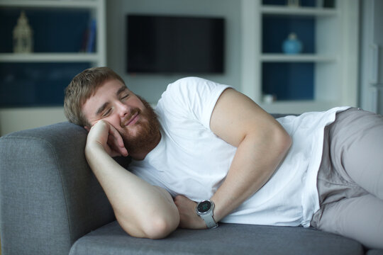 Sweet dreams. Serene millennial male lie on soft cozy couch in comfortable pose having tight sleep. Satisfied young guy nap on sofa at home enjoy good rest relax, man at living room at home 