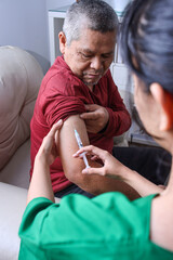 Young nurse makes injection in hand of old man. Concept of vaccination for older people.