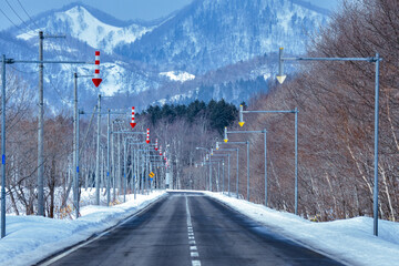 冬の北海道の山間部、センターラインと白い雪が残る道	
