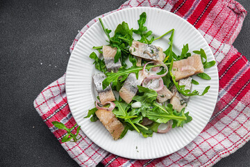herring pieces pickled onion, green arugula leaves meal food snack on the table copy space food background rustic top view  pescatarian diet