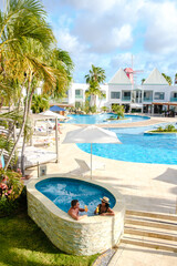 Fototapeta na wymiar Luxury resort with swimming pool near Palm Beach Aruba Caribbean, couple man and woman mid age on a luxury vacation in the Caribbean