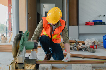 Structural worker dressed in safety gear and hard hat doing construction and using circular saw to work.