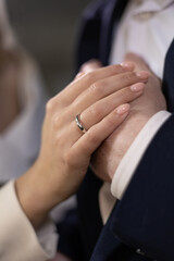 Girl holds hand on her partner's hand, pointing to their wedding rings in a close-up shot. Moment of emotional connection and unity. Focus is on details of hands, wedding rings, symbolizing love.