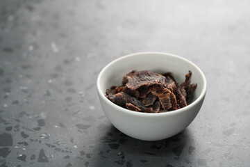 spiced beef jerky in white bowl on terrazzo countertop