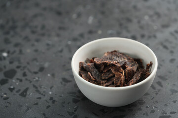 spiced beef jerky in white bowl on terrazzo countertop