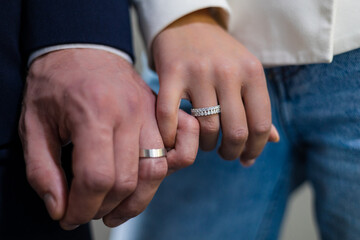 Luxurious jewelry boutique adorned with exquisite treasures, engaged couple intertwines their fingers with a gentle touch, proudly showcasing their shimmering diamond rings that sparkle in the light.