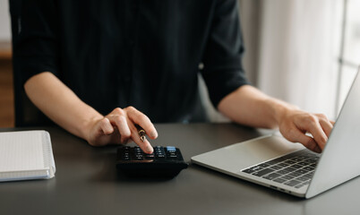 Close up of businesswoman or accountant hand typing laptop working to calculate on desk about cost at office.