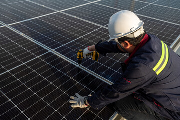 A Technicians power drill to install solar panels on the new roof of the factory. Solar power or Clean energy concept.