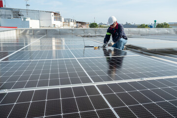 Asian engineer is using an electric meter and a laptop to check the power of solar panels on the...